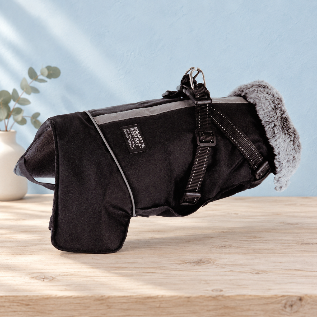Black Huntsman waterproof dog jacket on pale timber against a powder-blue backdrop