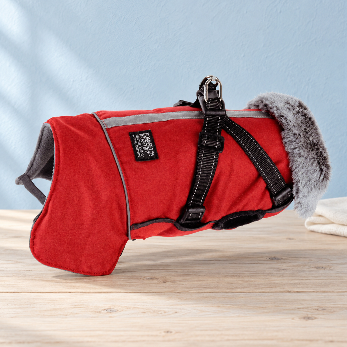 Red Huntsman waterproof dog jacket on pale timber against a powder-blue backdrop