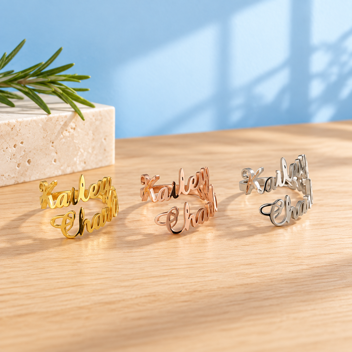 Personalised two-name stainless steel rings in Gold, Rose Gold and Silver against the Cary & Co blue background