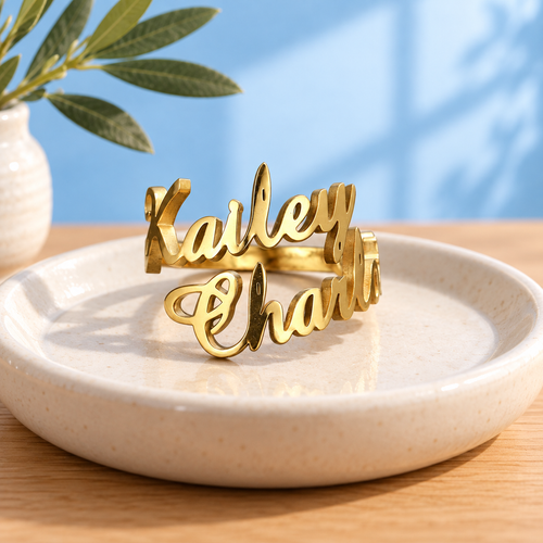 Personalised two-name stainless steel ring in Gold on an ivory dish against the Cary & Co blue background