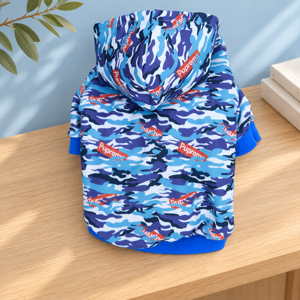 Blue camouflage dog hoodie on pale timber, showing the folded hood and back panel